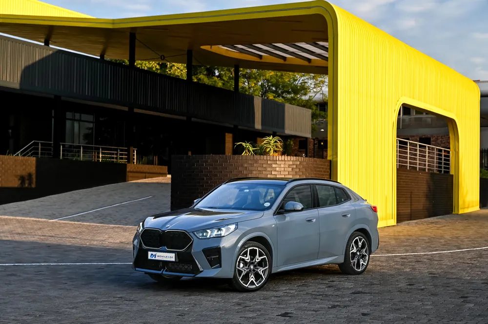 BMW X2 sDrive20i, tres cuartos delantero junto a un edificio con arco amarillo