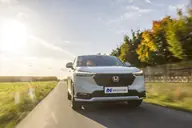 Honda HR-V Elegance, frontal en marcha por una carretera con árboles
