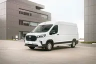 MAXUS Deliver 9 L3H2 Pro, tres cuartos delantero ante un edificio de oficinas, con aire alrededor