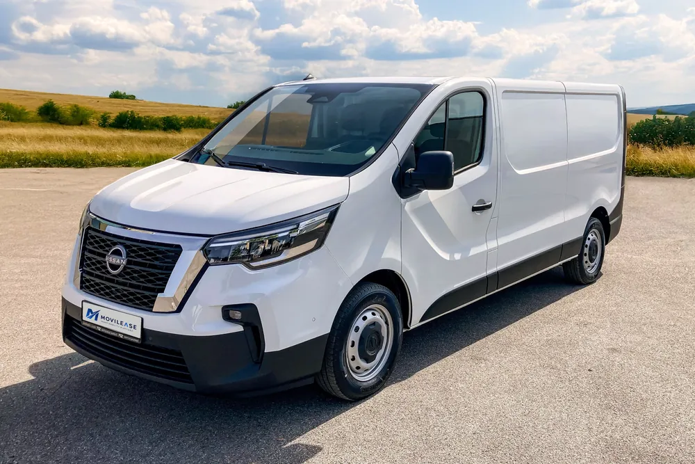 Nissan Primastar Furgón Acenta, tres cuartos delantero sobre asfalto con campo y nubes