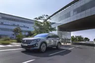 Renault Espace Techno E-Tech, tres cuartos delantero en marcha bajo un edificio de cristal