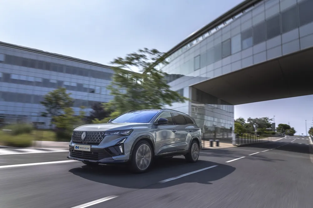 Renault Espace Techno E-Tech, tres cuartos delantero en marcha bajo un edificio de cristal