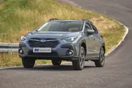 Subaru Crosstrek Hybrid Field, tres cuartos delantero en carretera de montaña con prado