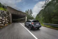 Subaru Crosstrek Hybrid Field, tres cuartos trasero en marcha junto a una galería de carretera